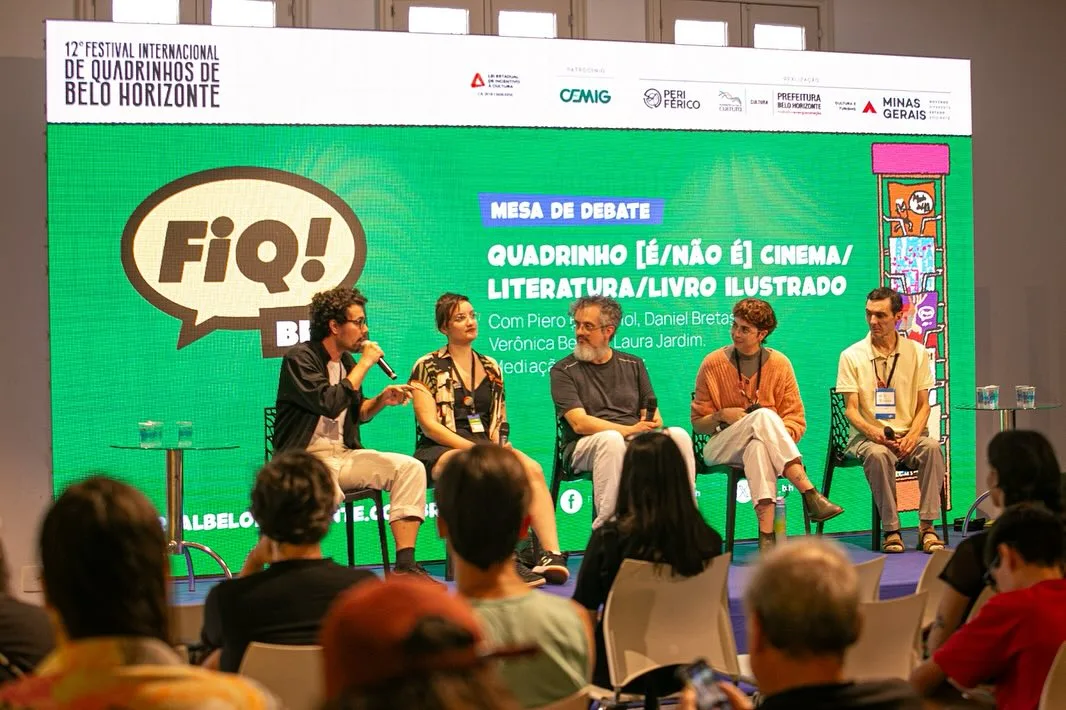 Painel de debate sobre quadrinhos, cinema, literatura e livro ilustrado no 12º Festival Internacional de Quadrinhos de Belo Horizonte, com cinco participantes em palco e público assistindo