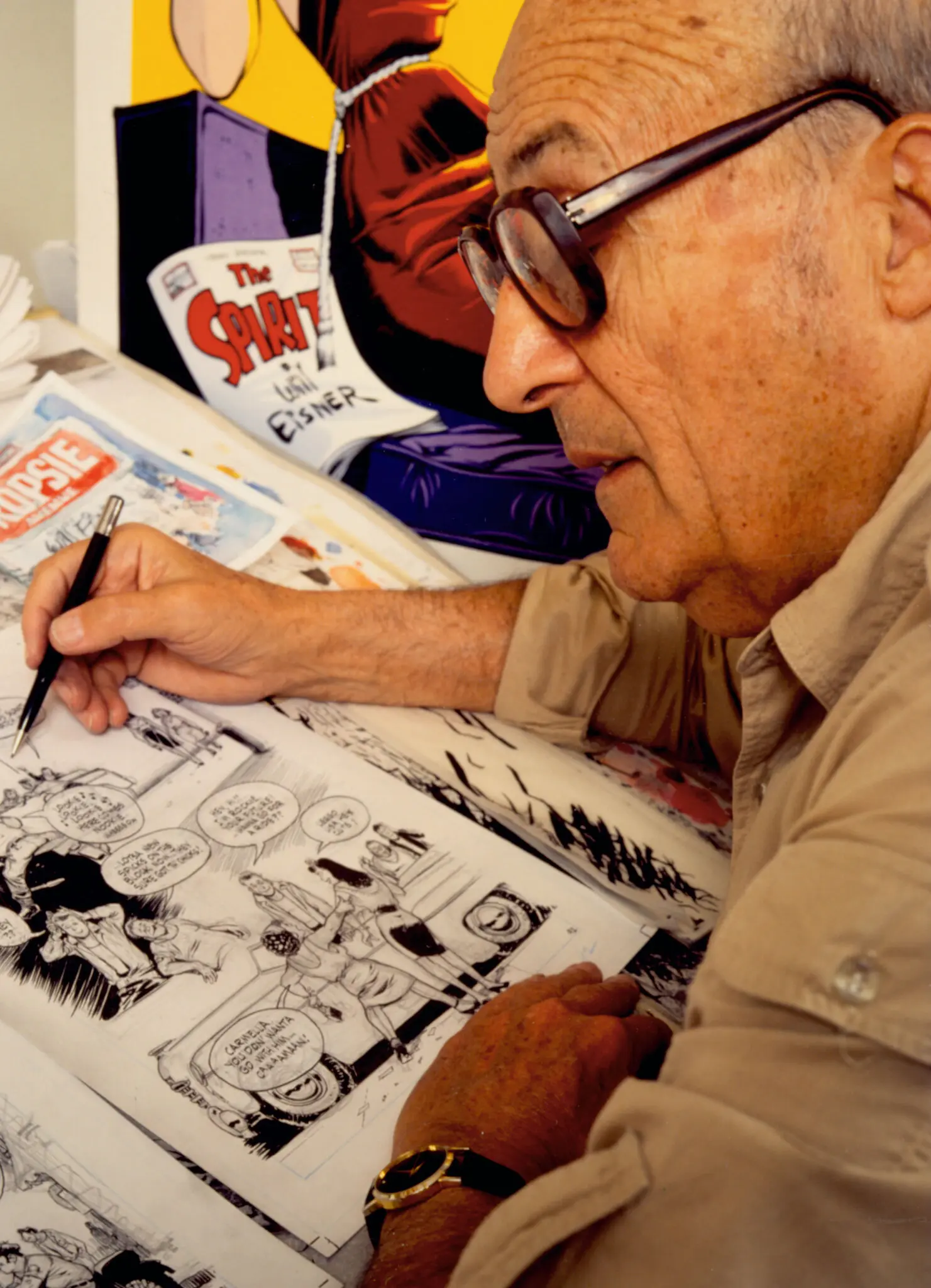 Will Eisner desenha uma HQ, com "The Spirit" ao fundo.