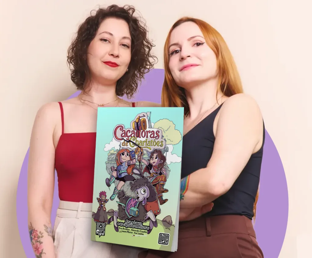 Duas mulheres jovens, uma com cabelos cacheados e outra com cabelos ruivos, posando ao lado de uma capa da HQ 'Caçadoras de Charlatões', uma história de aventura com personagens femininas e elementos fantasiosos.
